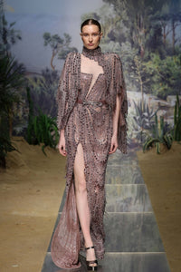 A model wearing a beige and brown animal print dress with long sleeves and a belt.